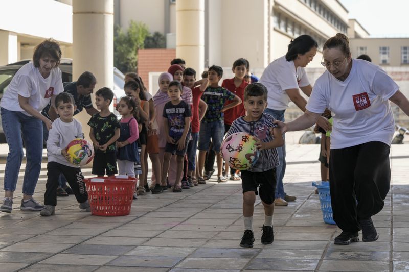 Volunteers of the Russian Cultural Center entertain displaced children at a school in Beirut, Lebanon, Thursday, Oct. 3, 2024, after fleeing the Israeli airstrikes in the south. (AP Photo/Bilal Hussein)