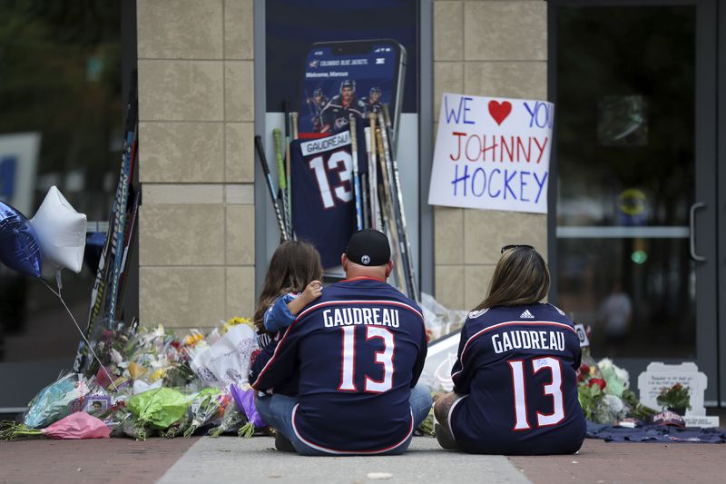 Shiloh Rivera, left, mourns with Hylas Stemen, center, and Amanda Rivera of Columbus, at the makeshift memorial set up by fans for Blue Jackets hockey player Johnny Gaudreau in Columbus, Ohio, Aug. 30, 2024. Gaudreau, along with his brother Matthew, was fatally struck by a motorist while riding his bicycle on Thursday. (AP Photo/Joe Maiorana)