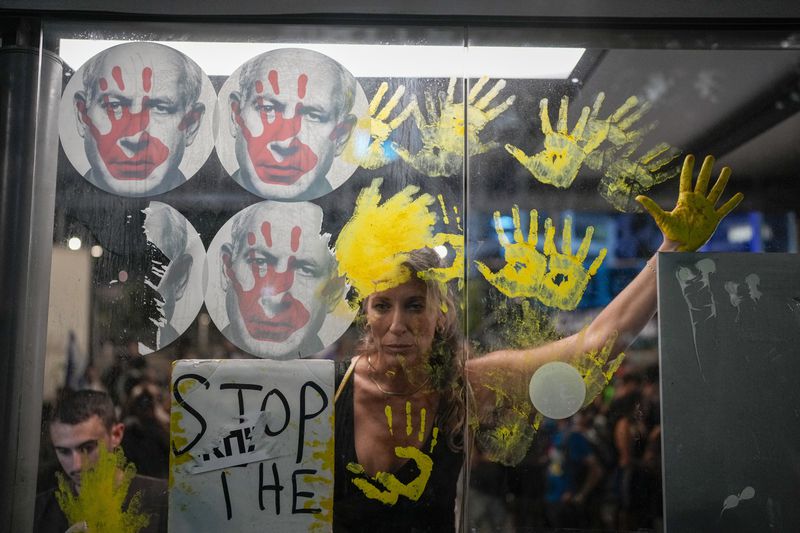 Demonstrators marks their hands on a window of a bus stop with photos of Israeli Prime Minister Benjamin Netanyahu, during a protest demanding a cease-fire deal and the immediate release of hostages held by Hamas in the Gaza Strip on Thursday, Sept. 5, 2024, in Tel Aviv, Israel. (AP Photo/Ohad Zwigenberg)