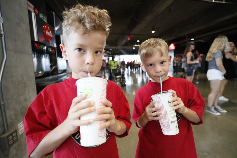 Twin brothers Richard and Daniel Doczi from Dalton enjoy a refreshing beverage using the new biodegradable straws that the Mercedes-Benz Stadium implemented on Sunday, July 17, 2022. The new blue drinking straw breaks down in the environment faster than a typical straw. Miguel Martinez /miguelmartinezjimenezajc.com