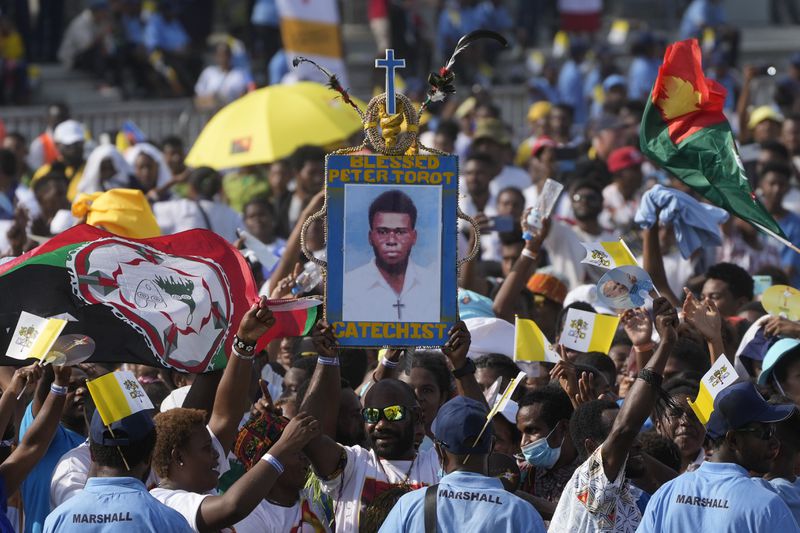 Attendees hoist a picture of blessed Peter To Rot, a catechist who was killed during the Japanese occupation in 1945 and beatified in 1995, during a meeting between Pope Francis and young people at the Sir John Guise stadium in Port Moresby, Monday, Sept. 9, 2024. (AP Photo/Gregorio Borgia)