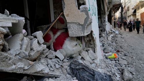 Palestinian refugees walk past rubble of a partly destroyed houses in the West Bank refugee camp of Tulkarem, Thursday, Sept. 12, 2024. (AP Photo/Nasser Nasser)