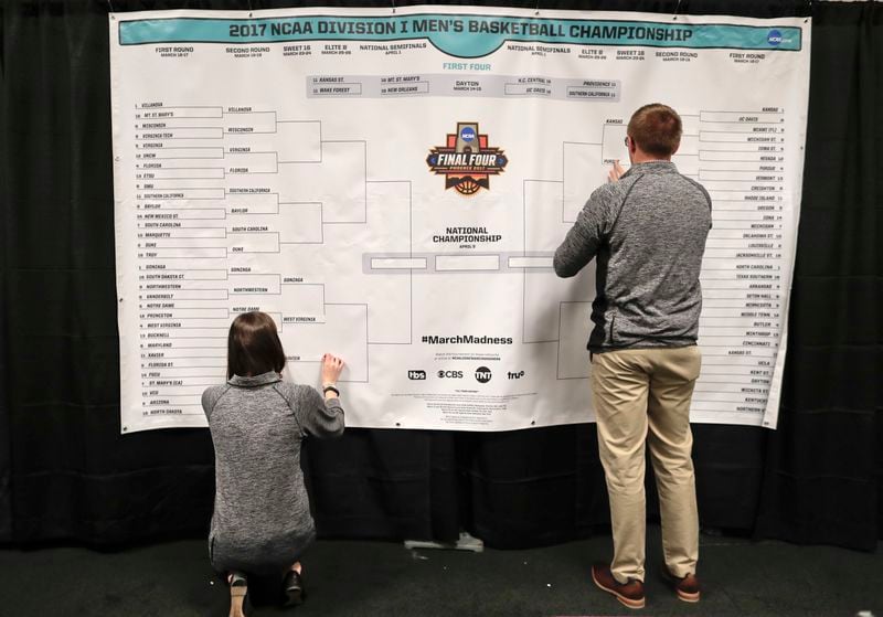 FILE - Staff members for the NCAA place the names of the teams in the Sweet 16 on a bracket in the media workroom before practices at the East Regional of the NCAA college basketball tournament in New York, March 23, 2017. The NCAA has presented a plan to Division I conference commissioners that would expand the lucrative men's and women's basketball tournaments by four or eight teams alongside an option to leave each field at 68 teams, according to a person familiar with the details. (AP Photo/Julie Jacobson, File)
