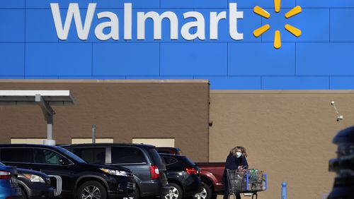 FILE - A woman wheels a cart with her purchases out of a Walmart store, Nov. 18, 2020, in Derry, N.H. (AP Photo/Charles Krupa, File)