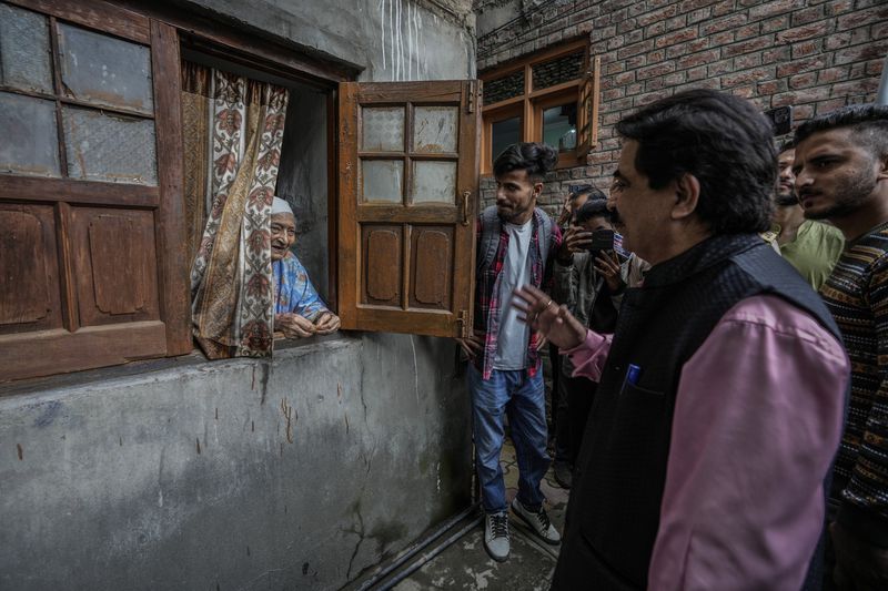 Ashok Bhat, right, a candidate of the Bharatiya Janata Party (BJP) talks to an elderly Kashmiri woman, while campaigning door-to-door ahead of the Jammu and Kashmir state assembly elections, in Srinagar, Indian controlled Kashmir, Thursday, Aug. 29, 2024. (AP Photo/Mukhtar Khan)