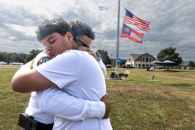 Ninth-grade student Jose Ortiz, left, is hugged by Georgia State Chaplain Ronald Clark as students and well-wishers arrived Thursday with flowers to place at the flagpole at Apalachee High School in Winder. A 14-year-old is accused of shooting and killing two fellow students and two teachers and injuring nine others Wednesday at Apalachee. (John Spink/AJC)