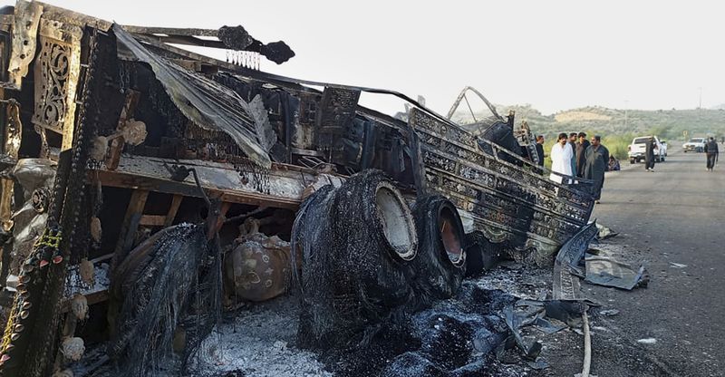 People look at a burnt-out vehicle that was set on fire by gunmen after they killed passengers on a highway in Musakhail, a district in Balochistan province in Pakistan's restive southwest, Monday, Aug. 26, 2024. (AP Photo/Rahmat Khan)