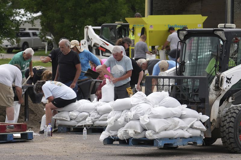 Volunteers help fill sandbags as heavy rains have caused both Tetonka Lake and Sakatah Lake to rise threatening to flood nearby homes and businesses Thursday, June 20, 2024, in Waterville, Minn. (Anthony Souffle/Star Tribune via AP)