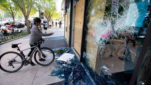 People stop to take photographs of the damage near the CNN center after the George Floyd protest Saturday, May 30, 2020. STEVE SCHAEFER FOR THE ATLANTA JOURNAL-CONSTITUTION