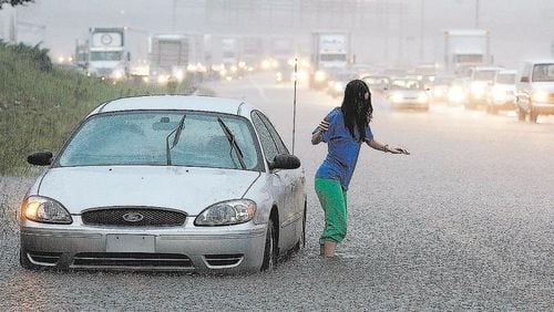 090921 Lilburn - RUSH HOUR MANIA - A female motorist abandons her flooded vehicle on I-75 South at spagetti junction as part of the highway becomes covered with water during rush hour on Monday, Sept. 21, 2009. A Georgia State patrolman arrived on the scene to help aid the motorist who declined to be identified.  Curtis Compton, ccompton@ajc.com