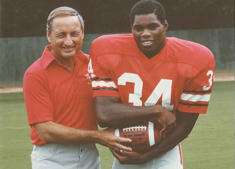Georgia coach Vince Dooley hands the ball off to freshman tailback Herschel Walker in a posed photo from the 1980 season. (Photo provided by UGA Athletics)
