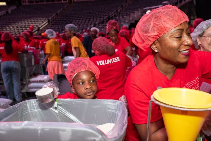 Cassidy Chisolm, 5, left, and her mom Cherisse  Chisolm mix ingredients for red lentil jambalaya kits for local food banks.    (Jenni Girtman for The Atlanta Journal-Constitution)