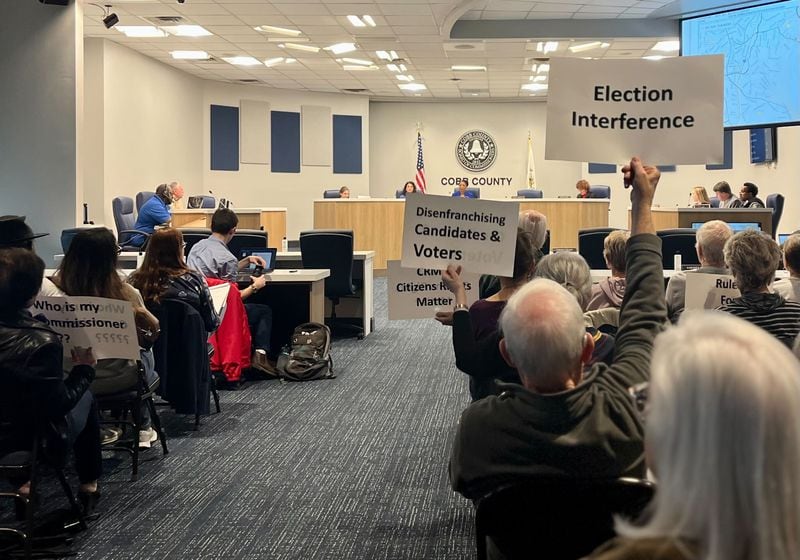 Residents hold signs in protest of the county's district map at a Cobb County Board of Elections and Registration meeting on Tuesday, March 5, 2024, in Marietta. (Taylor Croft/taylor.croft@ajc.com)