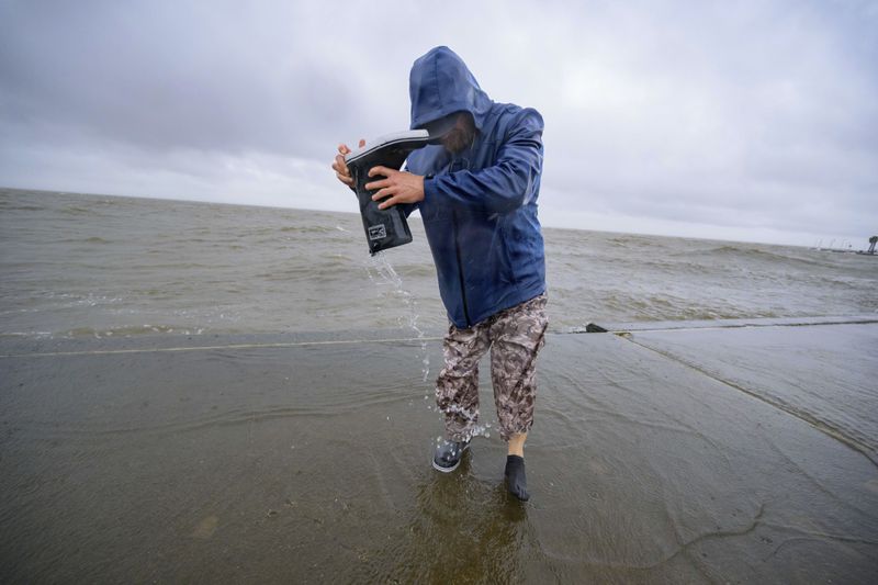 Conrad Bach drains water from his boot after getting doused while looking at waves from the wind from Hurricane Francine along Lakeshore Drive and Lake Ponchartrain in New Orleans, Wednesday, Sept. 11, 2024. (AP Photo/Matthew Hinton)