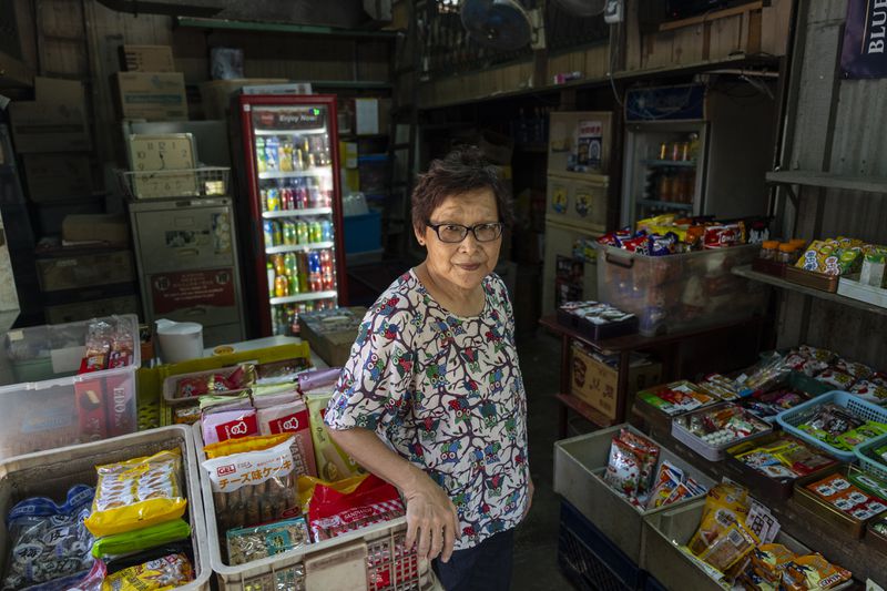 Teoh Bee Hua, a Malaysian who moved to Cha Kwo Ling after marrying a villager in 1973, poses for a photo at her grocery shop in the Cha Kwo Ling Village in Hong Kong, Sunday, Aug. 25, 2024. She has kept operating her grocery shop there even though she no longer lives in the village after a fire. (AP Photo/Chan Long Hei)