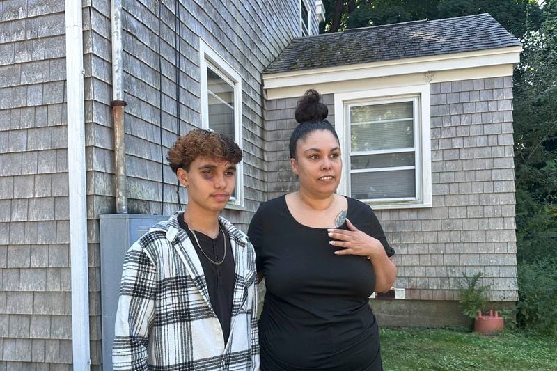 In a photo taken Sept. 4, 2024, in Gloucester, Massachusetts, transgender teenager Jayden Tkaczyk stands outside his house with his mother, Jasmine Tkaczyk. Jayden Tkaczyk alleges that he was beaten up at a party by several other high school students due his being transgender. (AP Photo/Michael Casey)