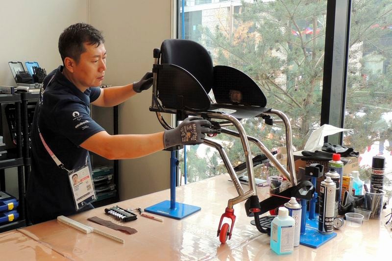 An Ottobock mechanic works on wheelchair in the Ottobock repair center at the Paralympic Village in Saint-Denis, near Paris, France, Saturday, Aug. 24, 2024. (AP Photo/Tom Nouvian)