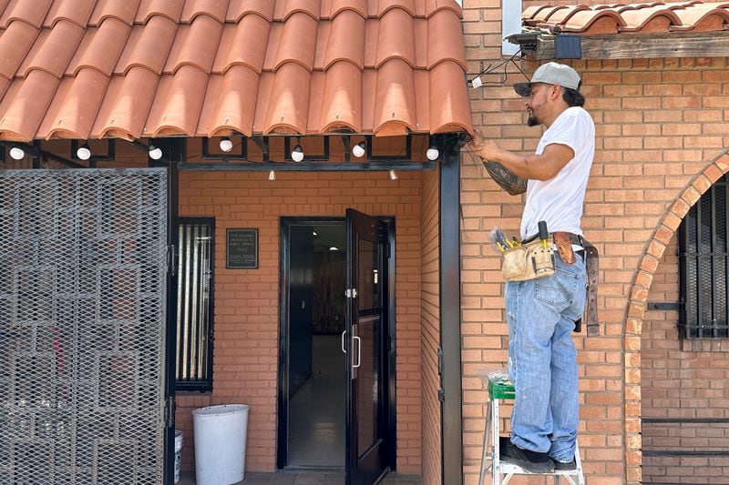 Luis Soto of Sunland Park, N.M. works on wiring and talks outside at his cannabis dispensary, Sunshine Essentials, Thursday, Aug. 22, 2024. The politics of immigration look different from communities on the Southwest border that are voting in hotly contested congressional races. Soto said migrants who cross the border have impacted his efforts to open the cannabis dispensary in a former small-town post office. He's a registered Democrat who remembers better economic times under former President Donald Trump. (AP Photos/Morgan Lee)