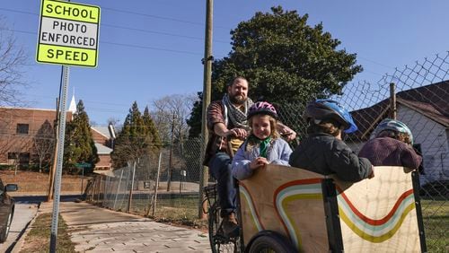 Brendan Horgan rides his bike with his children Fionnoula, 6, Bearach 4, and Ruairi’, 2, near the intersection of Metropolitan Parkway and Elbert Street in a school zone where cameras have been installed to prevent speeding on Wednesday, Jan. 31, 2024. (Natrice Miller/ Natrice.miller@ajc.com)