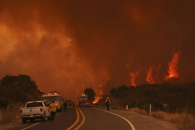 Firefighters monitor the Airport Fire as it advances Tuesday, Sept. 10, 2024, in El Cariso, an unincorporated community in Riverside County, Calif. (AP Photo/Eric Thayer)