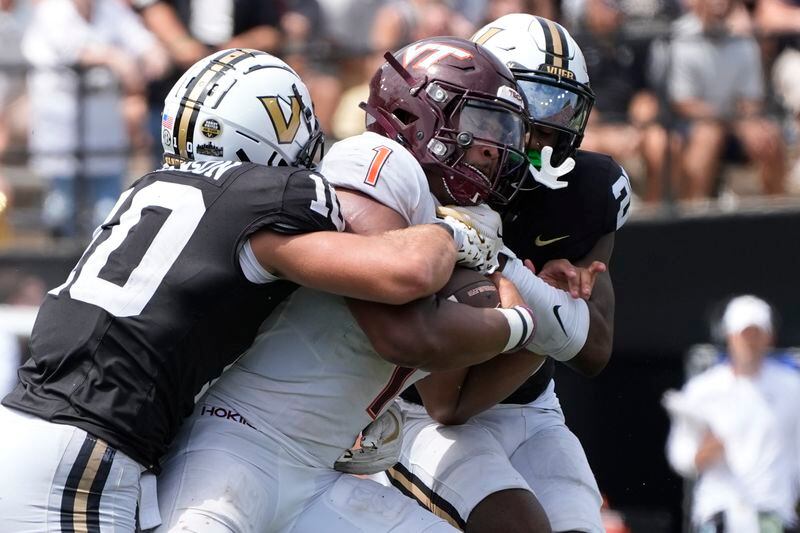 Virginia Tech quarterback Kyron Drones (1) is tackled by Vanderbilt linebacker Langston Patterson (10) and cornerback Martel Hight, right, during the second half of an NCAA college football game Saturday, Aug. 31, 2024, in Nashville, Tenn. (AP Photo/George Walker IV)