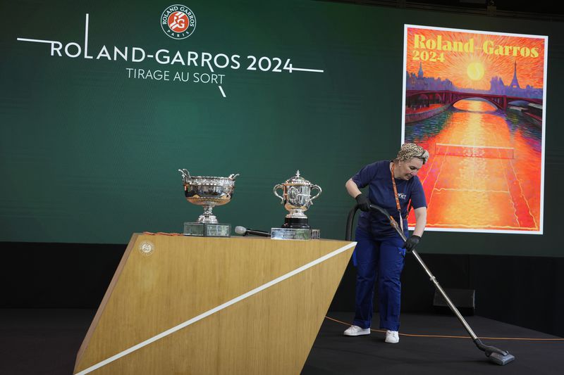 A woman cleans the stage before the draw for the French Tennis Open at the Roland Garros stadium, Thursday, May 23, 2024 in Paris. The tournament starts Sunday May 26, 2024. (AP Photo/Thibault Camus)