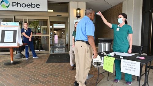 A  nurse checks a temperature of an employee before he enters the Phoebe Putney Memorial Hospital in Albany on Tuesday, March 24, 2020. Well off the interstate some 180 miles south-southwest of Atlanta, Albany's struggles with the coronavirus stick out like a sore thumb on the state's map. (Hyosub Shin / Hyosub.Shin@ajc.com)