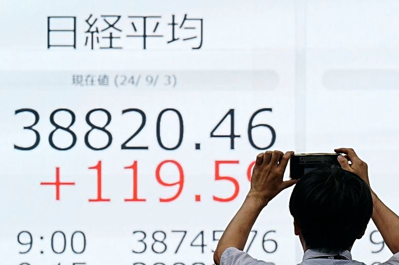 A person photographs an electronic stock board showing Japan's Nikkei index at a securities firm Tuesday, Sept. 3, 2024, in Tokyo. (AP Photo/Eugene Hoshiko)