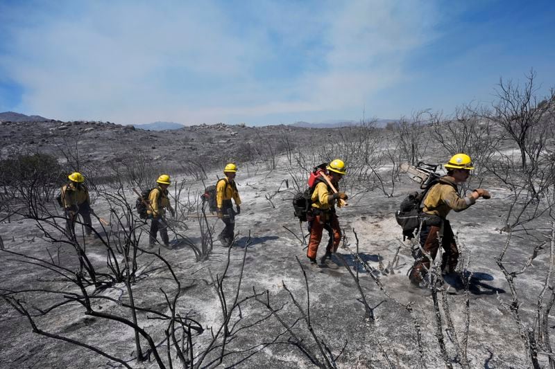 Members of Riverside County Cal Fire walk up a hillside while battling the Airport Fire Wednesday, Sept. 11, 2024, in El Cariso Village, in unincorporated Riverside, County, Calif. (AP Photo/Gregory Bull)