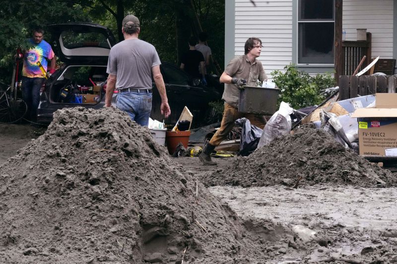 Walker Blackwell, right, cleans up the damage to his home after remnants of Hurricane Beryl caused flooding and destruction, Friday, July 12, 2024, in Plainfield, Vt. (AP Photo/Charles Krupa)