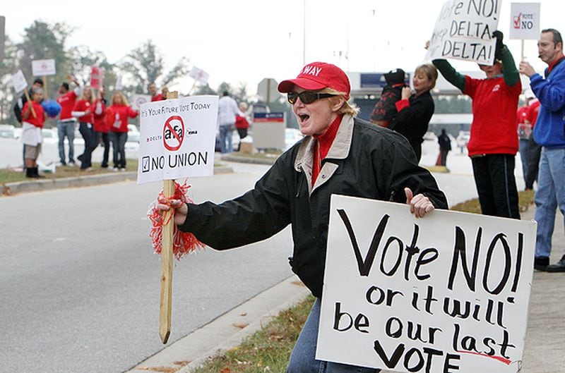 Katrina Evans (right) waves two protest signs as dozens of Delta flight attendants participate a lively anti-union rally in College Park in 2011. Labor organizers have tried multiple times to get a union vote for flight attendants, machinists and others at the Atlanta-based airlines.