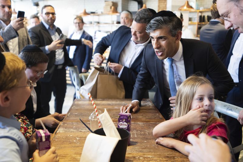 Britain's Prime Minister Rishi Sunak speaks with local children during a visit to a bakery in Golders Green, while on the general election campaign trail, in north west London, Sunday June 30, 2024. (James Manning/Pool Photo via AP)