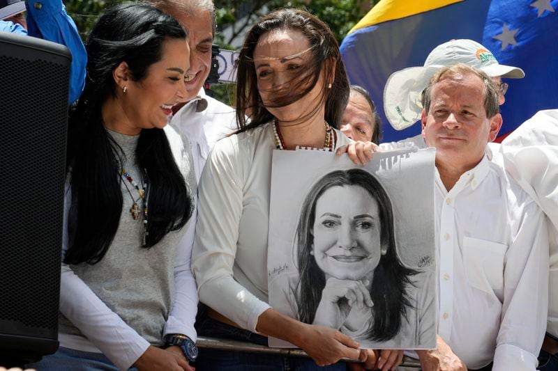 Opposition leader Maria Corina Machado holds a portrait of her, gifted to her by a supporter, during a protest against the reelection of President Nicolás Maduro one month after the disputed presidential vote which she says the opposition won by a landslide, in Caracas, Venezuela, Wednesday, Aug. 28, 2024. (AP Photo/Ariana Cubillos)