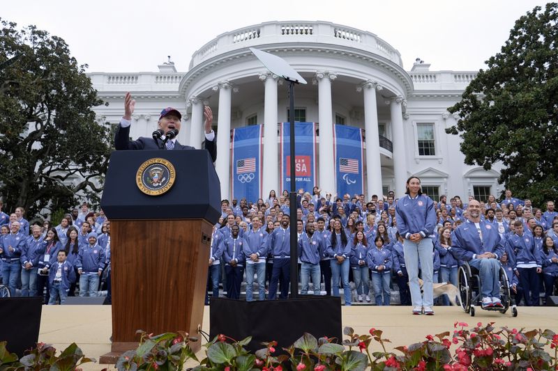 President Joe Biden, from left, speaks as Olympic swimmer Torri Huske and Paralympian basketball players Paul Schulte listen during at an event celebrating the 2024 U.S. Olympic and Paralympic teams on the South Lawn of the White House in Washington, Monday, Sept. 30, 2024. (AP Photo/Susan Walsh)