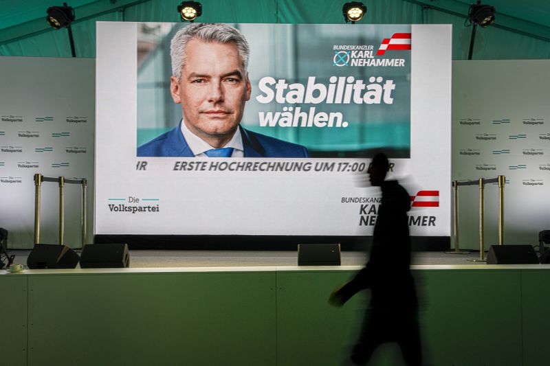 A person walks by a display showing electoral visuals of Austrian Chancellor Karl Nehammer at the OVP, Austrian People's Party, headquarters in Vienna, Austria, Sunday, Sept. 29, 2024, after casting his vote in the country's national election. (AP Photo/Andreea Alexandru)