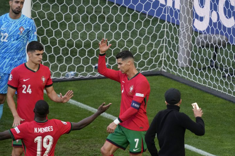 Portugal's Cristiano Ronaldo and his teammates react after a pitch invader ran towards him during a Group F match between Turkey and Portugal at the Euro 2024 soccer tournament in Dortmund, Germany, Saturday, June 22, 2024. (AP Photo/Michael Probst)
