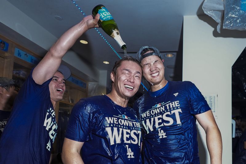 Los Angeles Dodgers designated hitter Shohei Ohtani, right, and teammate Yoshinobu Yamamoto, center, celebrate with others after the Dodgers defeated the San Diego Padres 7-2 in a baseball game to clinch the National League West division Thursday, Sept. 26, 2024, in Los Angeles. (AP Photo/Ashley Landis)