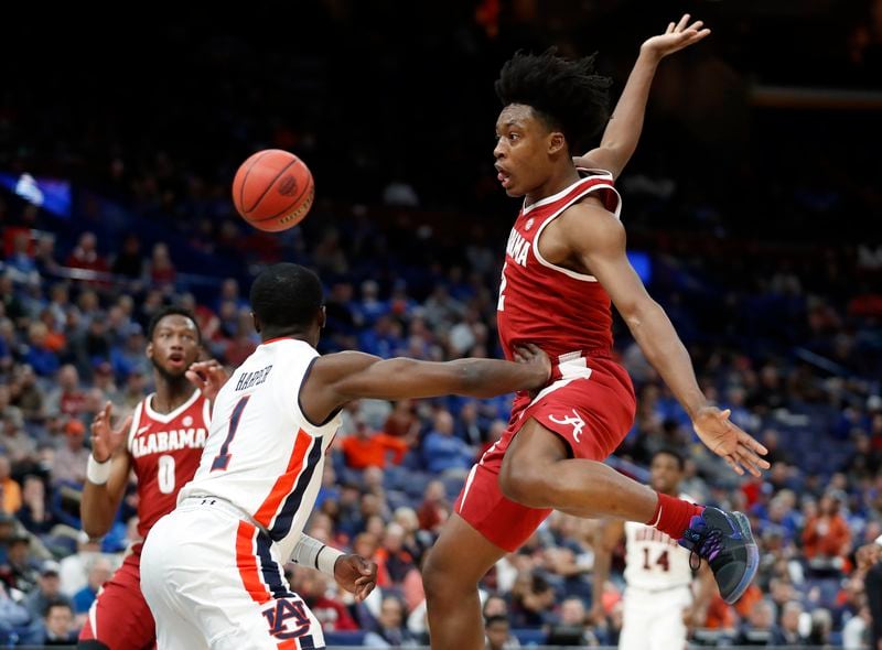 Alabama's Collin Sexton, right, makes a no-look pass to teammate Donta Hall, left, around Auburn's Jared Harper, center, during the second half in an NCAA college basketball quarterfinal game at the Southeastern Conference tournament Friday, March 9, 2018, in St. Louis. Alabama won 81-63. (AP Photo/Jeff Roberson)