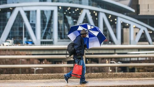 Dwayne Smith holds off the rain with his umbrella as he passes the Philips Arena. Atlanta is still free of snow, but it's under a winter weather advisory.