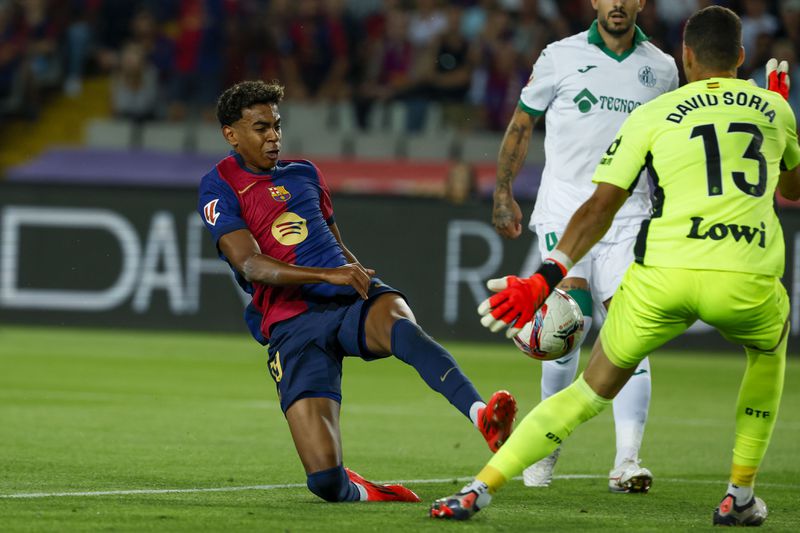 Getafe's goalkeeper David Soria, right, makes a save in front of Barcelona's Lamine Yamal during a Spanish La Liga soccer match between Barcelona and Getafe at the Olympic stadium in Barcelona, Spain, Wednesday, Sept. 25, 2024. (AP Photo/Joan Monfort)