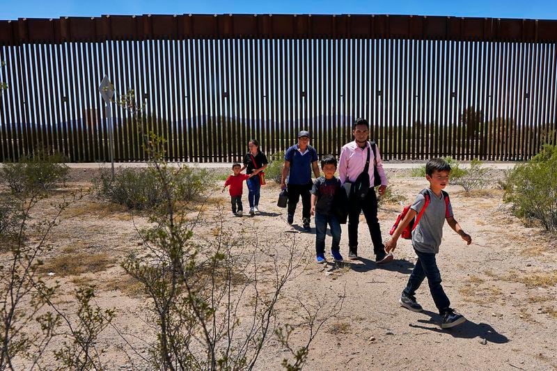 FILE - A family of five claiming to be from Guatemala and a man stating he was from Peru, in pink shirt, walk through the desert after crossing the border wall in the Tucson Sector of the U.S.-Mexico border, Tuesday, Aug. 29, 2023, in Organ Pipe Cactus National Monument near Lukeville, Ariz. (AP Photo/Matt York, File)