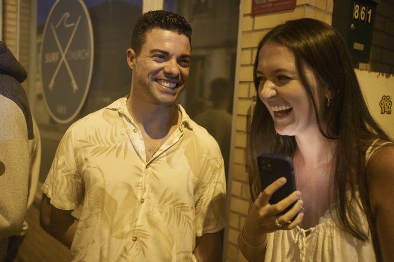 Surf Church pastor, the Rev. Samuel Cianelli, and church member Lydia Fleete laugh outside the church in the suburbs of Porto, Portugal on Sunday, Aug. 18, 2024. (AP Photo/Luis Andres Henao)