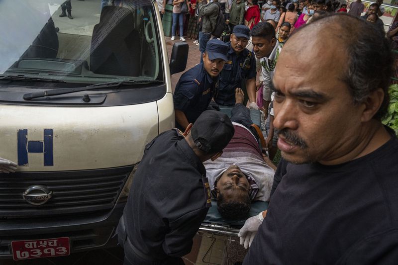 An injured man is brought for treatment at a hospital, after a bus carrying Indian tourists fell into a river near Abukhaireni town about 75 miles west of the capital Kathmandu, Nepal, Friday, Aug. 23, 2024. (AP Photo/Niranjan Shrestha)