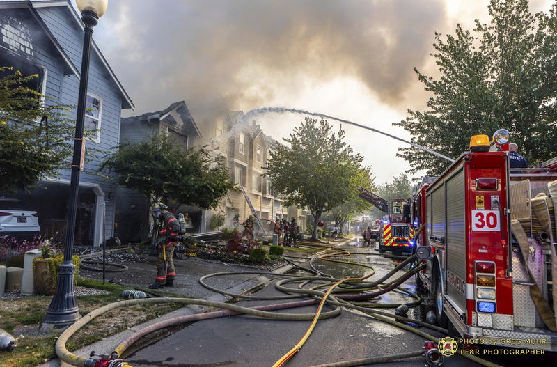 In this photo provided by Portland Fire & Rescue, multiple fire companies, including Gresham Fire, Portland Fire & Rescue, Clackamas, and Vancouver Fire, positioned hose lines to extinguish the primary building involved and adjacent structures after a small plane crashed Saturday, Aug. 31, 2024, in Fairview, Ore. (Greg Muhr/Portland Fire & Rescue via AP)