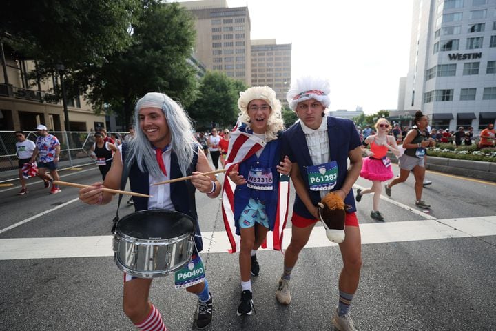 Costumed runners celebrate at the start of the 55th running of the Atlanta Journal-Constitution Peachtree Road Race in Atlanta on Thursday, July 4, 2024.   (Miguel Martinez / AJC)