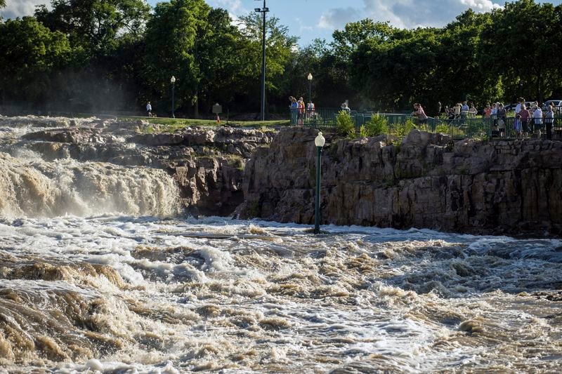 Visitors view the rising floodwaters at Falls Park, Saturday, June 22, 2024, in Sioux Falls, S.D., after days of heavy rain led to flooding in the area. (AP Photo/Josh Jurgens)