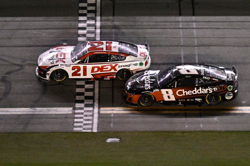 Harrison Burton (21) crosses the finish line ahead of Kyle Busch (8) to win a NASCAR Cup Series auto race at Daytona International Speedway, Saturday, Aug. 24, 2024, in Daytona Beach, Fla. (AP Photo/Phelan M. Ebenhack)