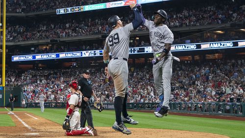 New York Yankees' Jazz Chisholm Jr., right, celebrates his three-run home run with Aaron Judge, center, as Philadelphia Phillies catcher J.T. Realmuto, left, looks on during the seventh inning of a baseball game, Tuesday, July 30, 2024, in Philadelphia. (AP Photo/Chris Szagola)