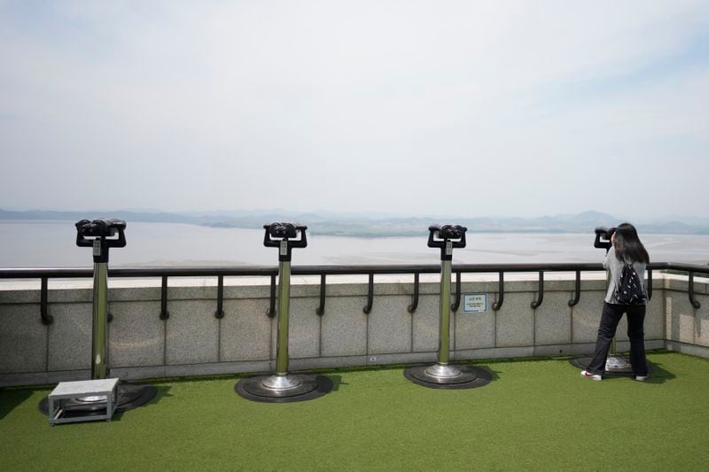A visitor uses binoculars to see the North Korean side from the unification observatory in Paju, South Korea, Friday, June 21, 2024. On Friday, South Korea’s military said it had fired warnings shots the previous day to repel several North Korean soldiers who briefly crossed the military demarcation line that divides the countries while engaging in unspecified construction work. Because of an overgrowth of foliage, the North Koreans may not have seen the signs marking the thin military demarcation line that divides the DMZ into northern and southern sides since the 1950-53 Korean War. (AP Photo/Lee Jin-man)