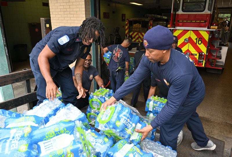 Sergeant Jathan Dortch (right) and other Atlanta firefighters unload bottled waters which will be distributed at Atlanta Fire Station #16, Saturday, June 1, 2024, in Atlanta. A water main that ruptured, causing thousands to lose access to water around Atlanta, was repaired Saturday morning but water may take several hours to be restored.(Hyosub Shin / AJC)